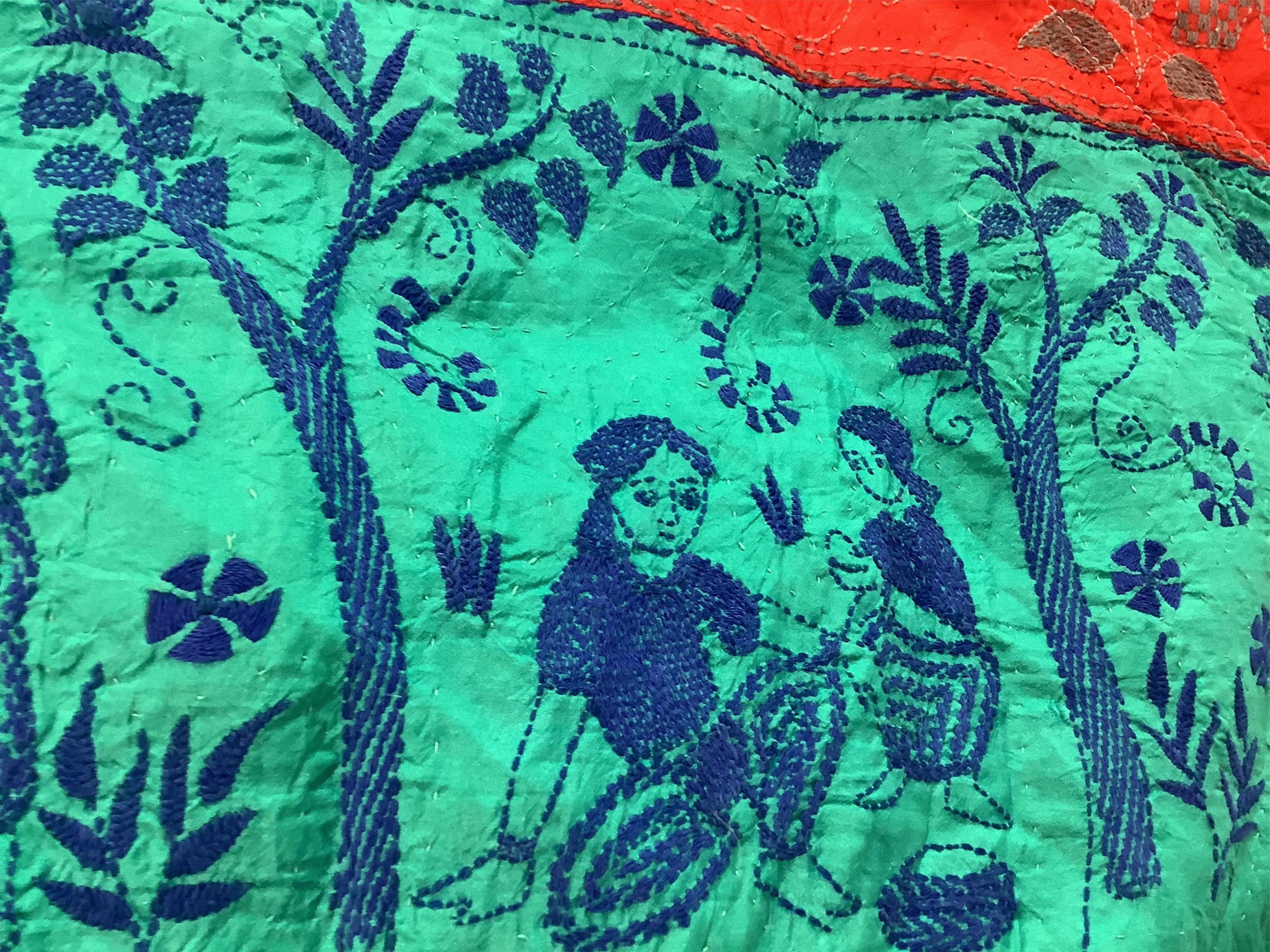 An Indian 20th century embroidered silk hanging, with decorative triangular tasselled edges. Worked in colourful silk stripes, with varying silk embroidered all over motifs. Bordered with colourful silk, beaded, tasselle
